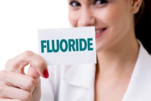 Dentist holding a Fluoride text card