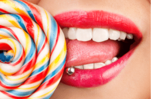 Pierced tongue while licking lollipop.